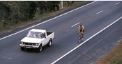 An image of a cyclist and a vehicle.
