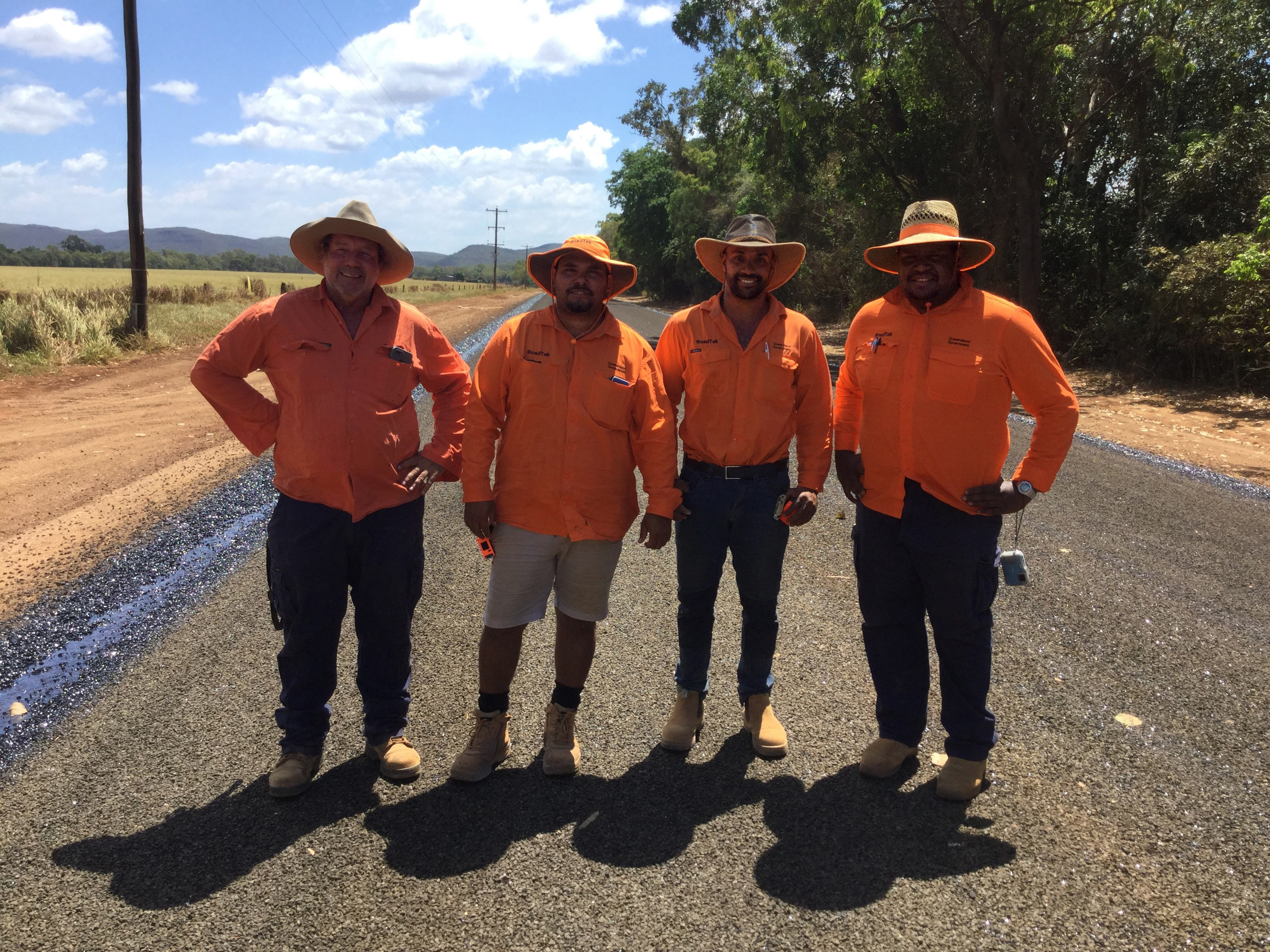 4 people in high vis gear standing on a newly paved road