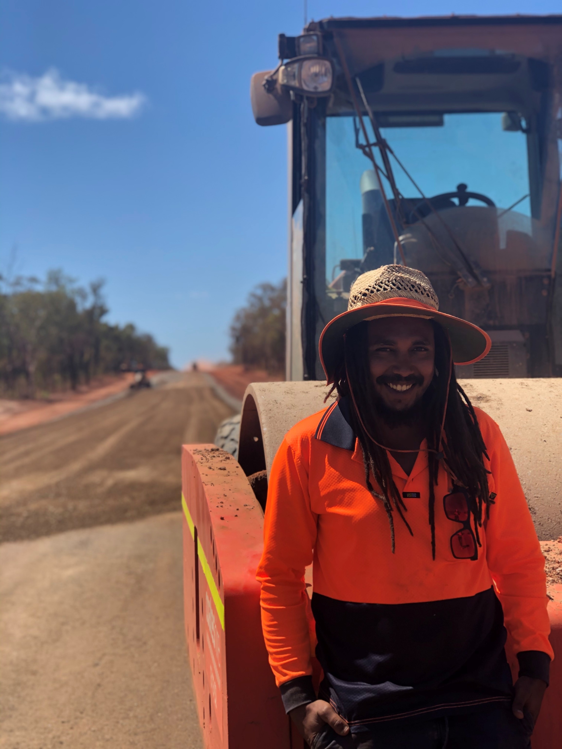 A person in high vis gear in front of road plant