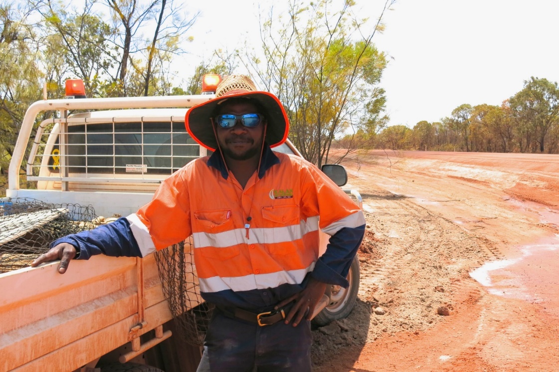 A man in high vis gear wearing sunglasses next to a ute