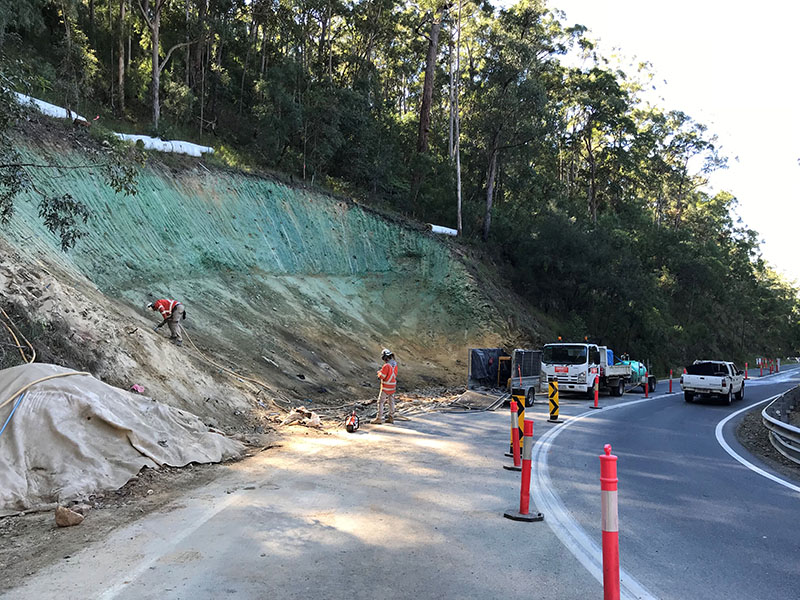 Abseiler grouts anchors on Beechmont Road