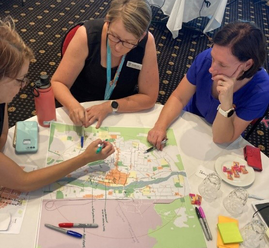 Photo of 3 people sitting at a table, drawing on a city map, participating in the Mt Isa stakeholder engagement workshop