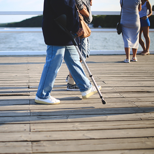 Person walking with a crutch.