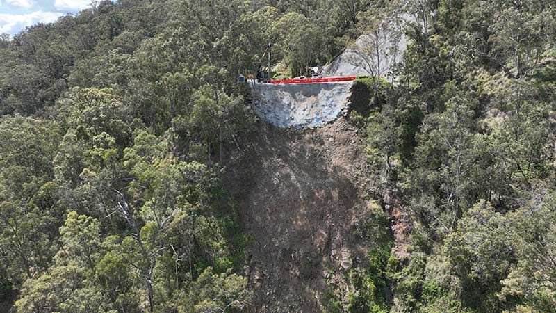 Aerial image of a steep slope with green trees and rockface where repairs have been made to a major landslip on Lamington National Park Road