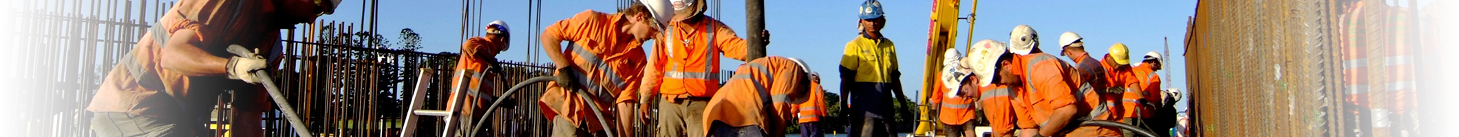 A group of people in safety uniforms working construction in between fences.