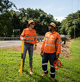 Surveyors in hi-vis clothing standing beside a road.