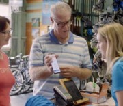 A man showing his phone screen to an employee of a business, showing her his Digital Licence app.