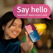 Woman holding her phone screen forward with the Queensland Digital Licence app splash screen on it. A speech bubble reads ‘Say hello Queensland’s Digital Licence is here.’