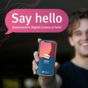 Young man holds his phone forward, with the Queensland Digital Licence app splash screen on it. A speech bubble reads ‘Say hello Queensland’s Digital Licence is here’