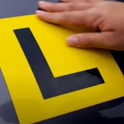 A close up picture of an L-plate, a black L against a yellow background.