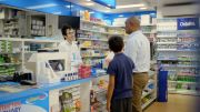 A man and a boy in a chemist, talking over the counter to the chemist.