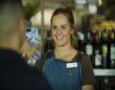 A woman smiling while looking at a phone screen that is being shown to her
