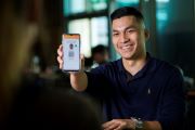 A man in a dark shirt holding his phone, showing the Digital Licence app to the camera.