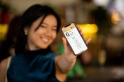 A woman holding her phone, showing the Digital Licence app to the camera