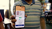 A person holding out a phone screen, with information on the screen, including their face, name, date of birth, Licence number and more.