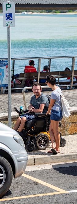  Man in powered wheelchair under a disability parking sign