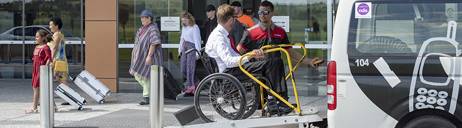 Business man in non-powered wheelchair being lifted in chair lift in maxi cab at regional airport.