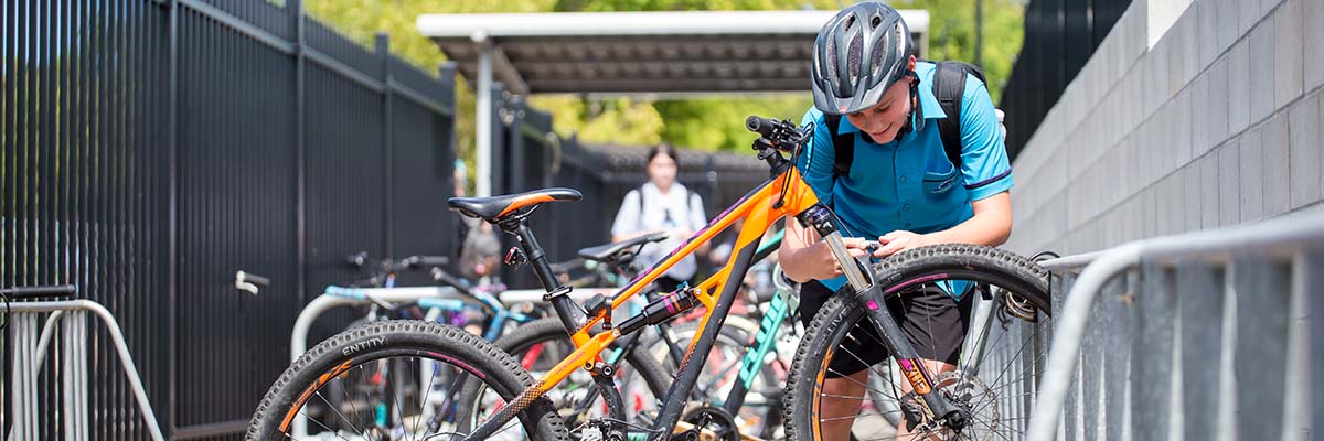 A child in a school uniform locking a bike to a bike rack