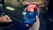 A hand holding a phone with the words Digital Licence and the Queensland Government coat of arms on the screen.