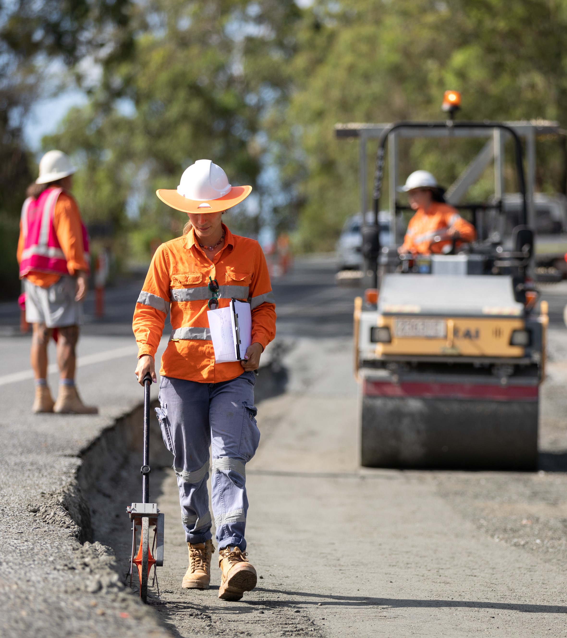 Worker in high visibility measuring on the side of a road