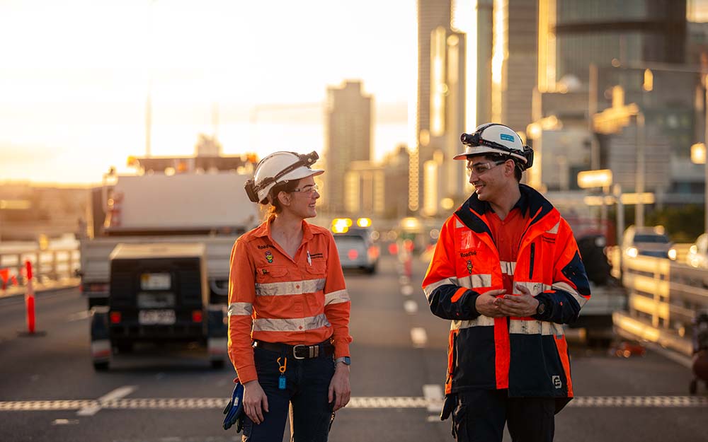 Two people in high visibility work wear standing on a road