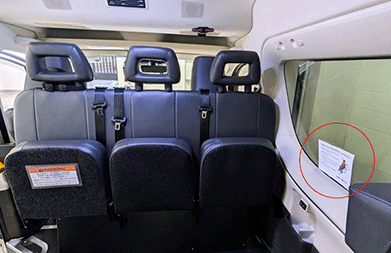 View from the back door of a wheelchair taxi showing a sticker placed on the bottom left quadrant of the front right-hand side window in the passenger bay.