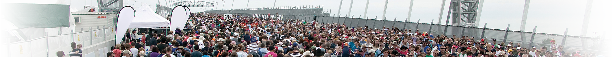 A crowd of people walking on a bridge.