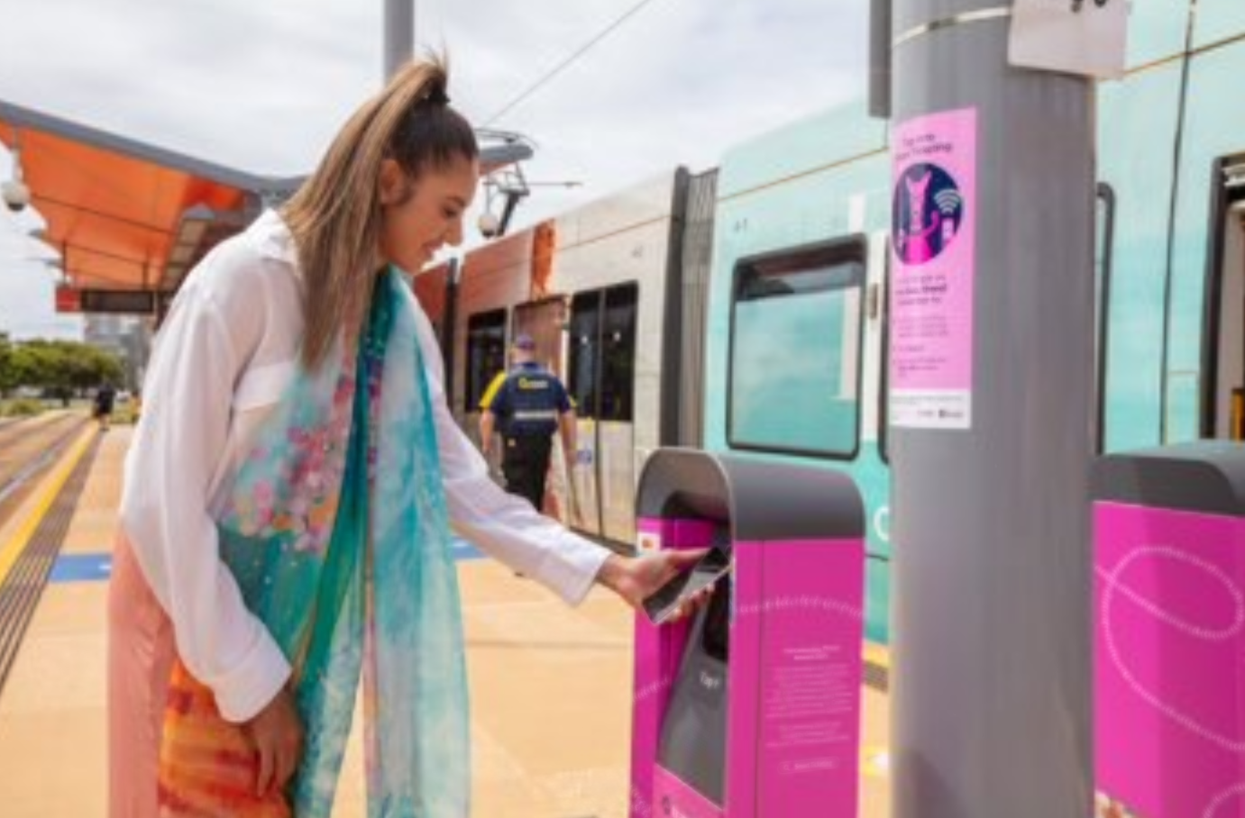 Taliqua using a Smart Ticketing machine in front of a Marlu poster