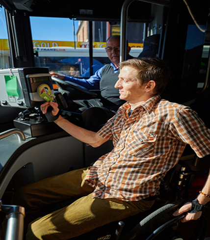 Person in a wheelchair scanning off a bus with the bus driver in the driver seat of the bus.