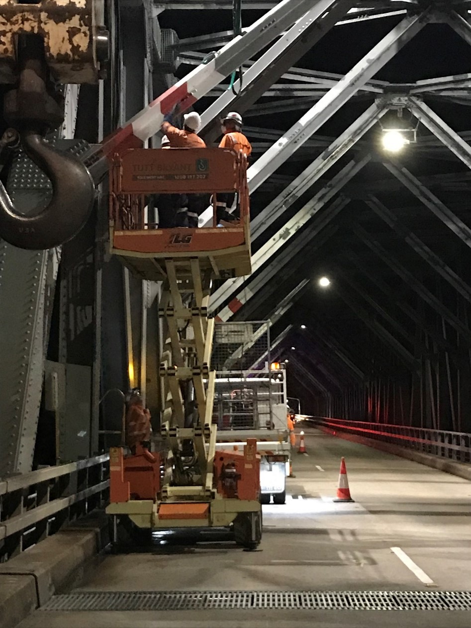 2 workers within an extended scissor lift assessing the bridge.