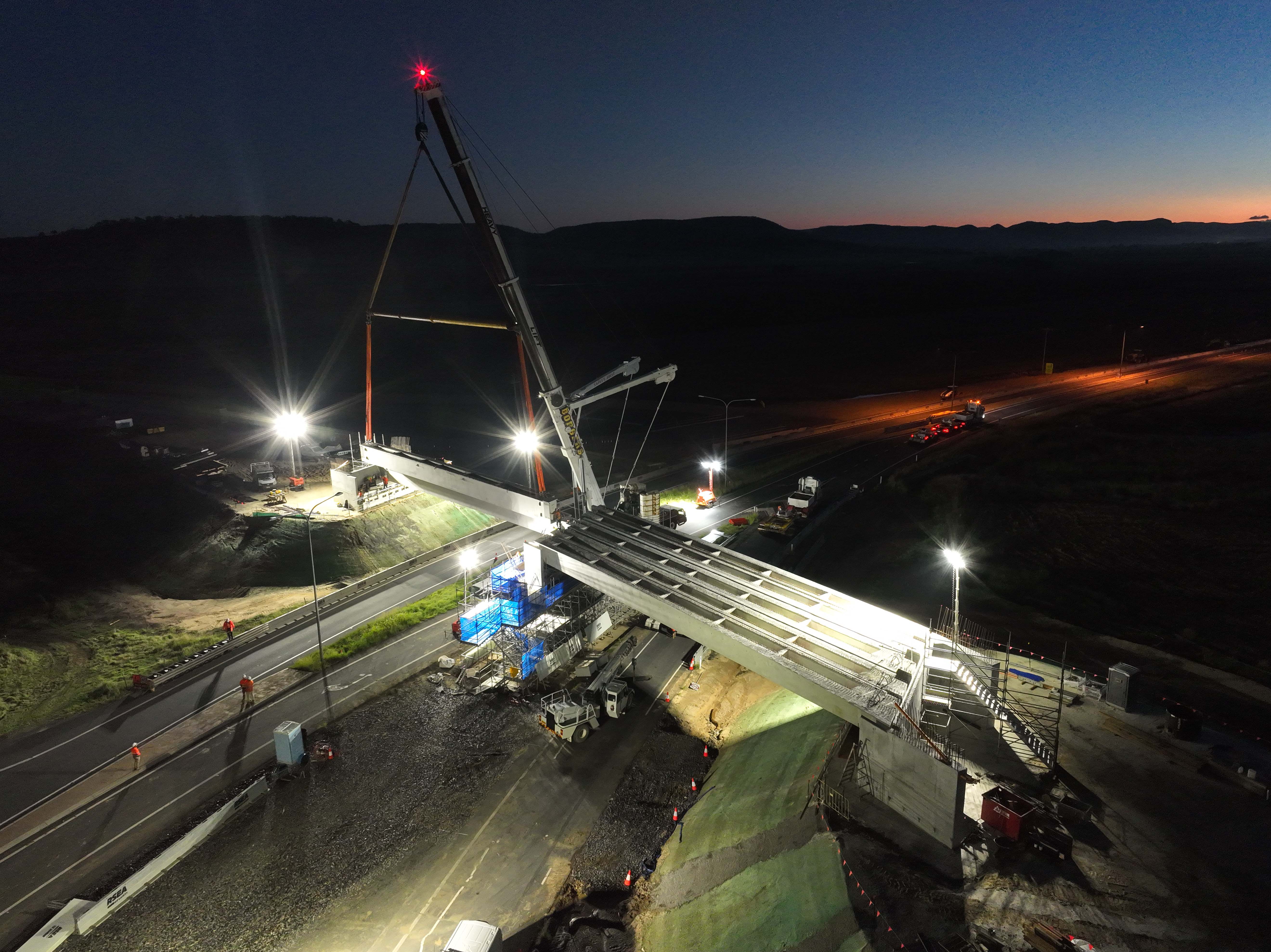 Image of a super T girder being lowered into place for the overpass at Eight Mile intersection in March 2022