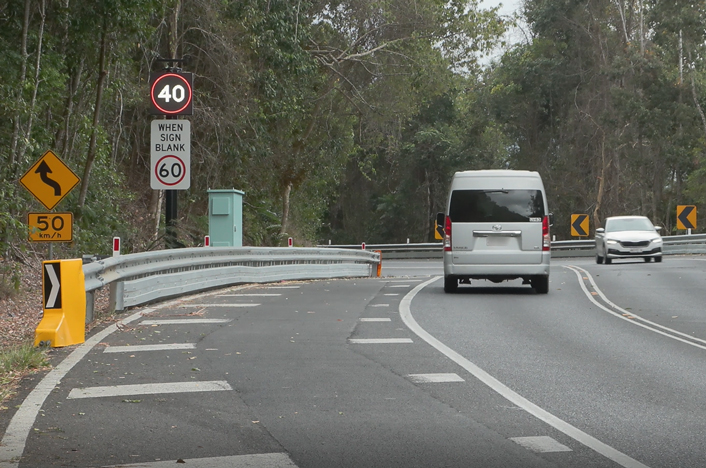 A section of Kuranda Range Road with a car driving up and mini van driving down. The variable speed limit sign shows a speed limit of 40 km/h.