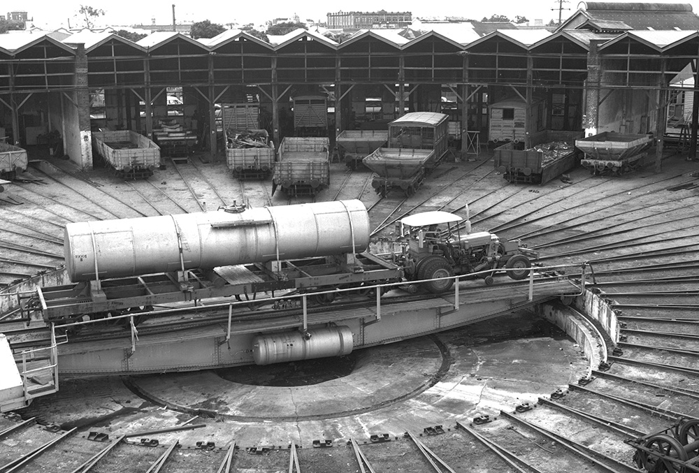 Roundhouse turntable in use – Image courtesy of Queensland Rail Historical photo of the Roundhouse turntable in use with multiple freight wagons picture in the background”