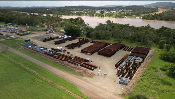 Rockhampton Ring Road new bridge location looking northeast across the Fitzroy River from Pink Lily where the exclusion zone will be in place. Foreground shows construction laydown area with bridge construction materials, mid-field shows Fitzroy River, and background shows Riverside estate on the northside of the river with Mount Archer in the background.