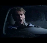 An image of a man yawning while driving a car