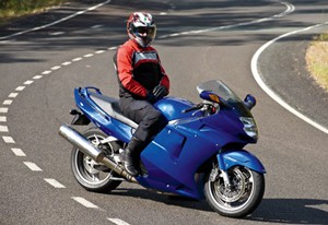Photo of a person in a safety outfit and helmet, sitting on a motorbike