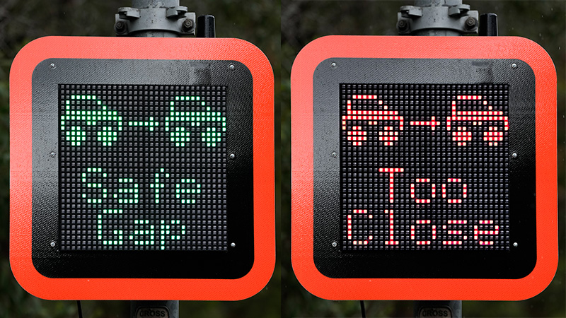 Two digital signs with one displaying 'Safe gap' in green and the other displaying 'Too close' in red.