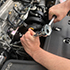 Man's hands using tool in car engine
