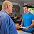 Man standing at service centre counter pointing to form held by male customer standing on other side of counter