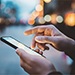 Person holding mobile phone in one hand while other hand is hovering over the screen to touch the screen