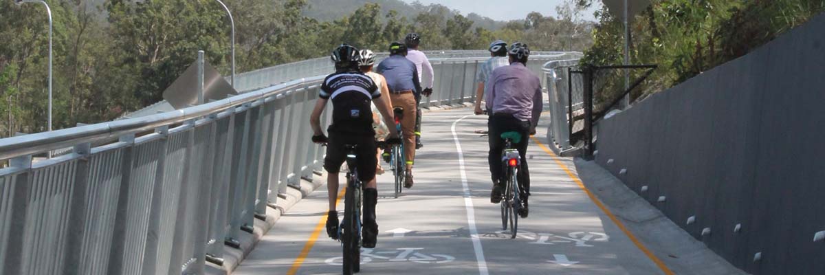 6 people riding bikes on a shared path with railings on both sides