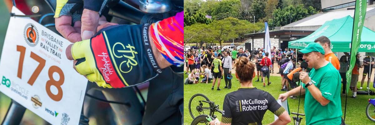 Side-by-side image. On the left, a pair of hands in bike riding gloves attach a sign that says, "Brisbane Valley Rail Trail" and has a large number and some logos to a bike frame. On the right, a crowd of people, some in bike riding clothes, stand in a grassy open area, near a pop up marquee and some flags. In the foreground a man speaks into a microphone. Some bikes are partially visible.