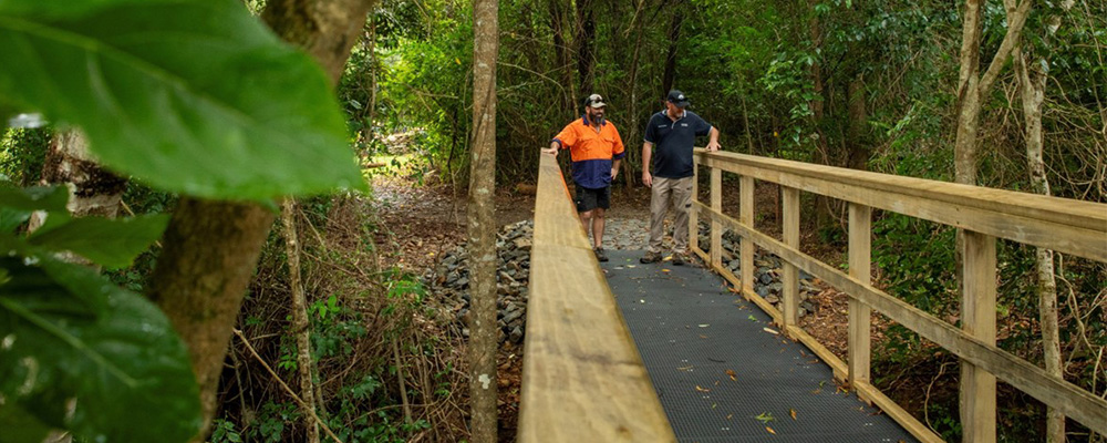 Two people walking along a bridge in the Palm Cove to Ellis Beach section of the Wangetti Trail. 