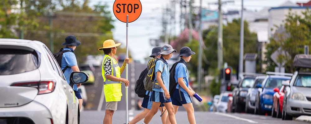 A group of students safely crossing a street on their way to school. 