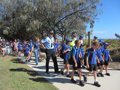 Image of children being walked to school by volunteers and police