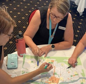3 people sitting around a table looking at a map